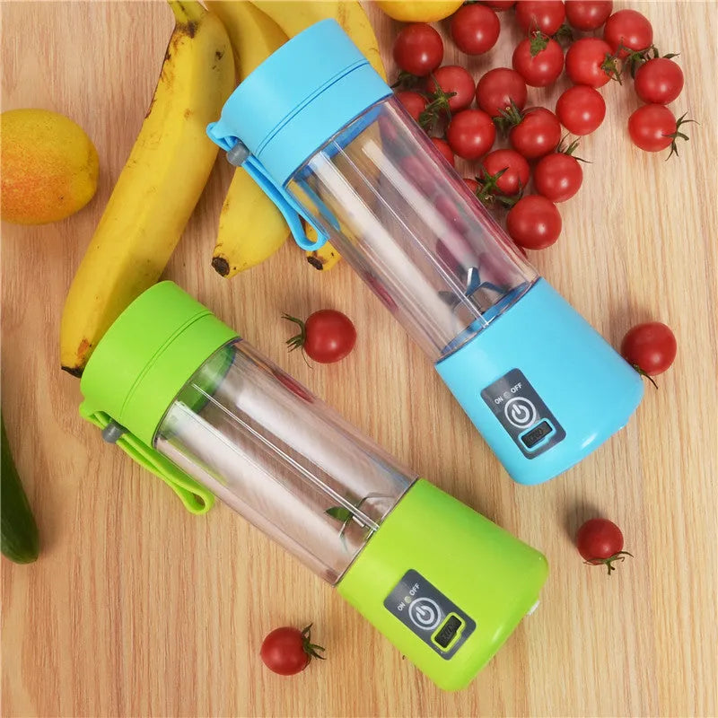 Mini USB electric fruit juicer with pink 400ml cup and stainless steel blades on a table.