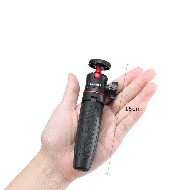 Black red and white aluminium mini tripod and extendable selfie stick for mobile phones on a desk.