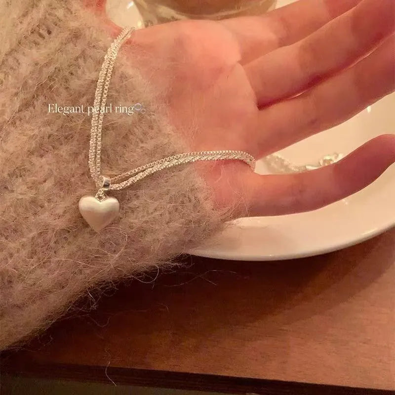 Women's brushed heart-shaped double-layer pendant necklace with adjustable chain on white background