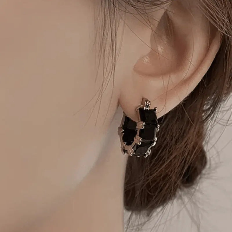 Geometric U-shaped gold earrings with black crystal zirconium stones in round design