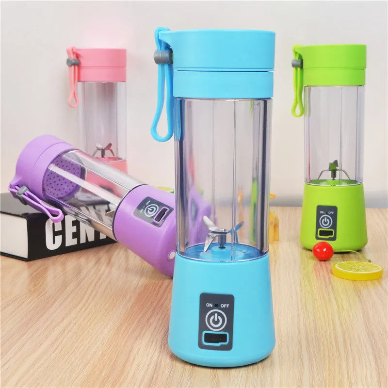 Mini USB electric fruit juicer with pink 400ml cup and stainless steel blades on a table.