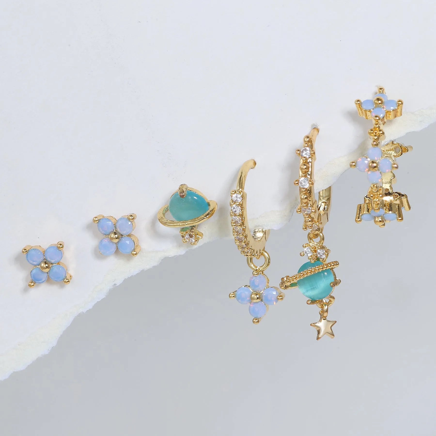 Gold and silver flower shaped stud earrings with a central zircon stone, showing front and back.