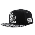 Cotton baseball cap with embroidered letters in black or white, showing adjustable strap and dome crown.