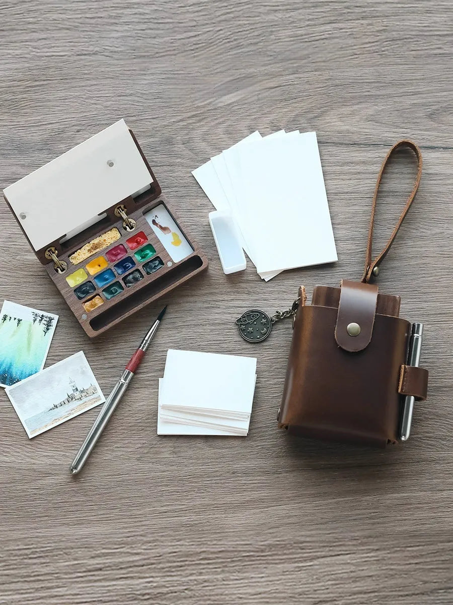 Mini walnut wood watercolour paint box open showing pigment colours inside with paint brush