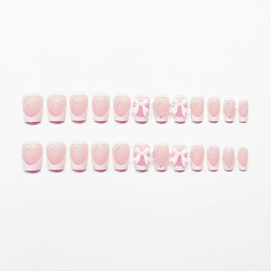 Short square French manicure artificial nails with white bow and floral patterns.