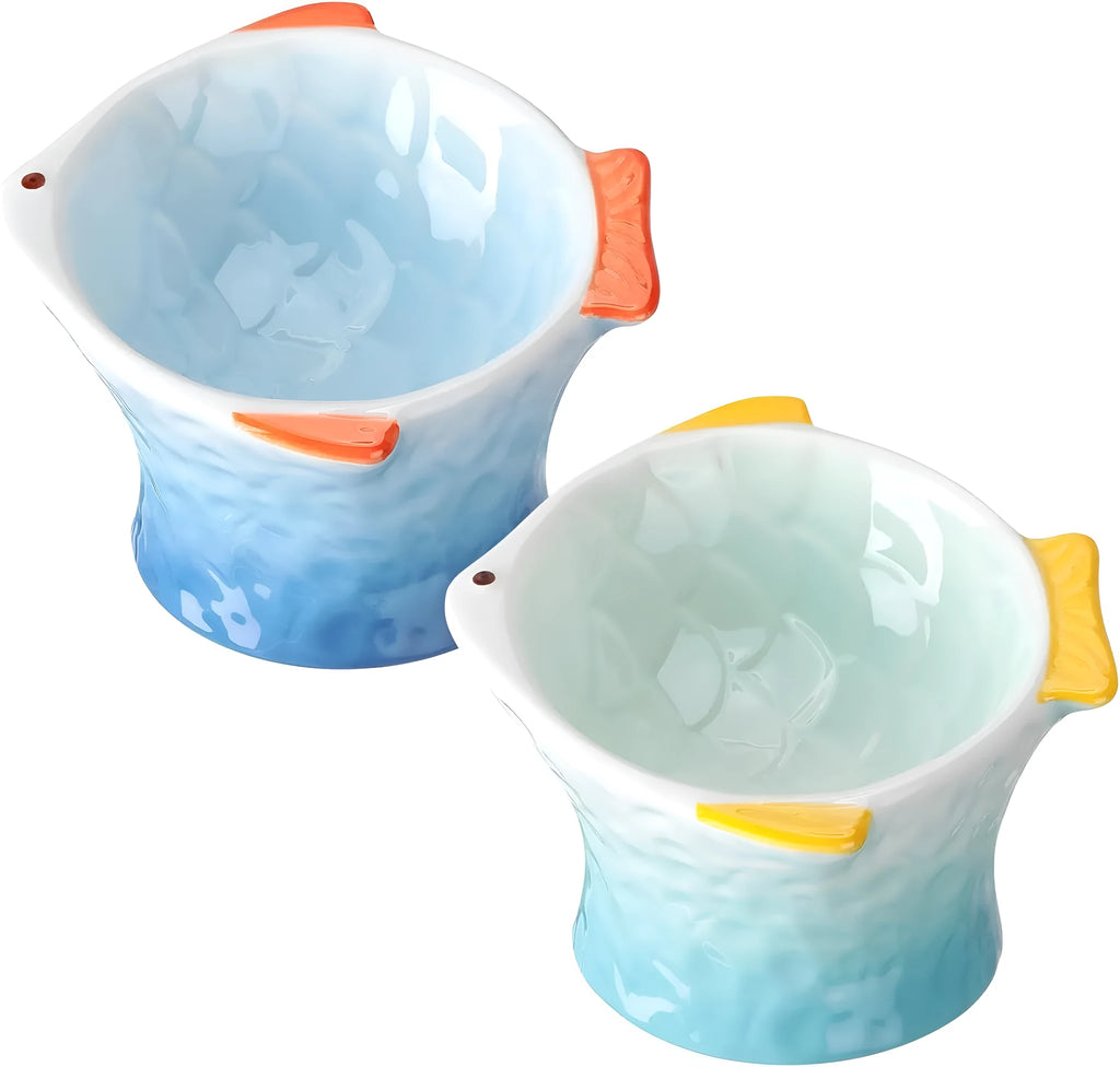 Set of blue fish-shaped ceramic cat bowls with a tilted angle on a wooden surface.