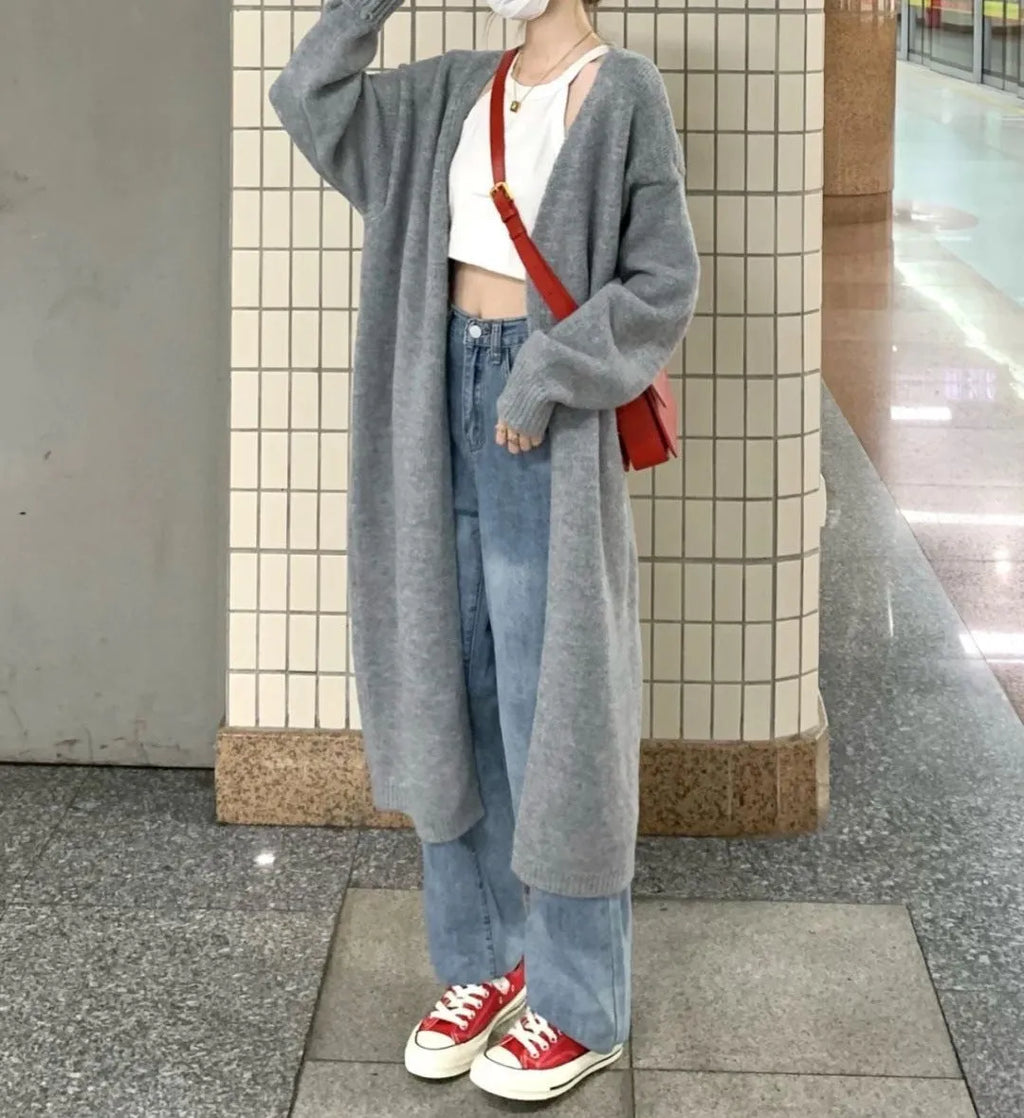 Woman wearing a loose, thick-knit chenille cardigan in a solid colour, showing the long sleeves and casual fit.
