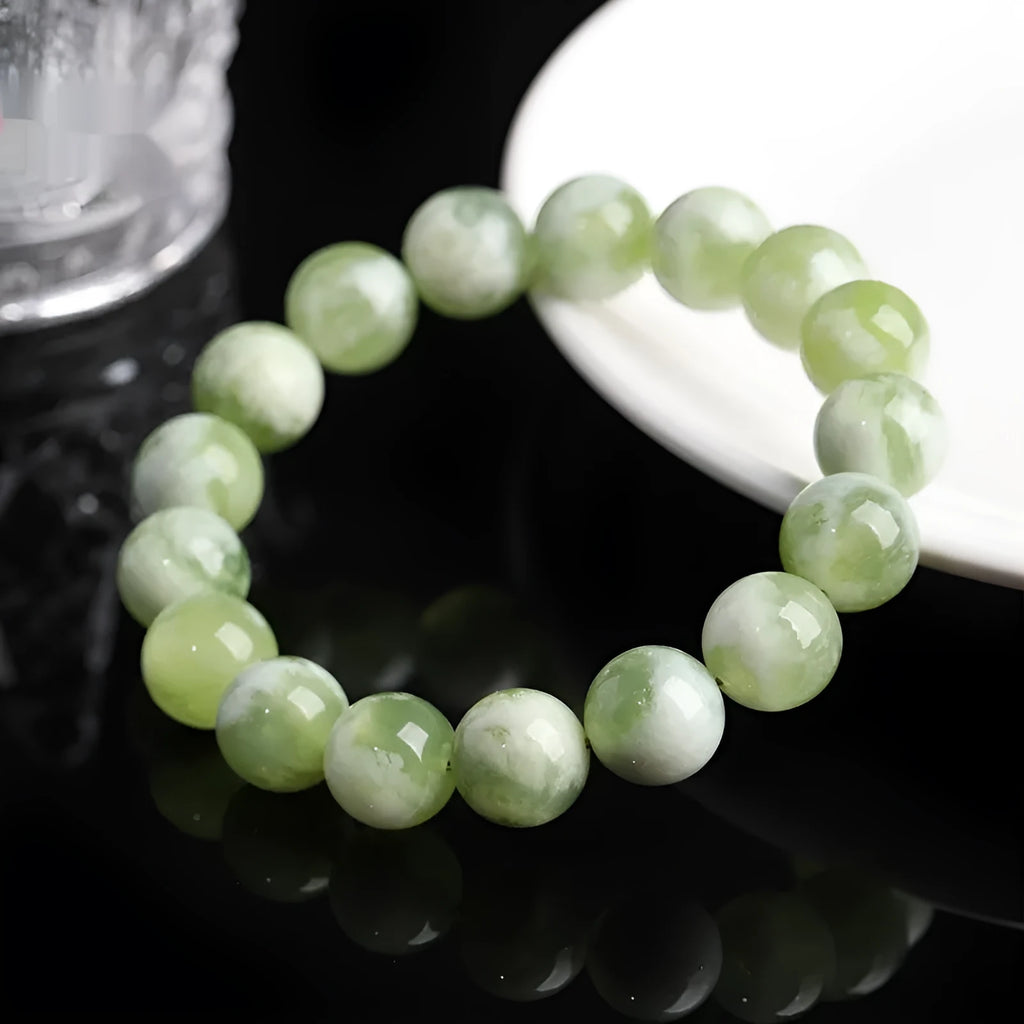 Polished green milk-in-water Xiuyan jade bracelet showing single circle of beads on a wrist.