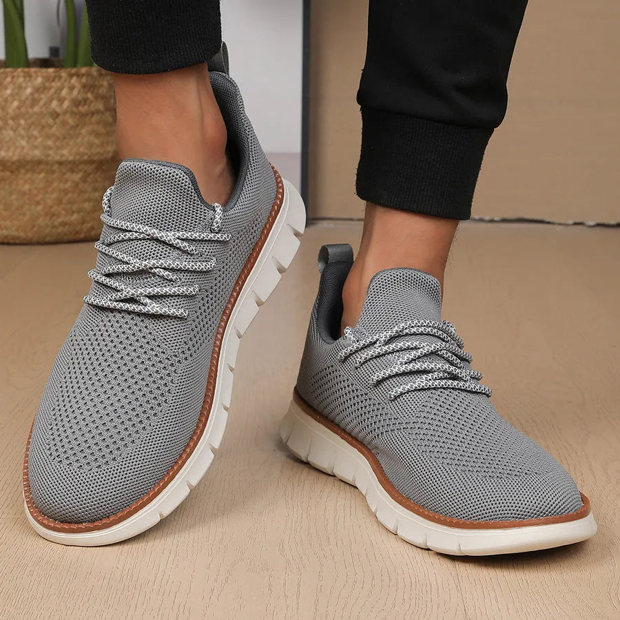Men's grey and black low-top casual sneakers with woven mesh fabric upper and round toe.