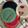 Handwoven round jute placemat with tassel edge in original hemp colour on a wooden table