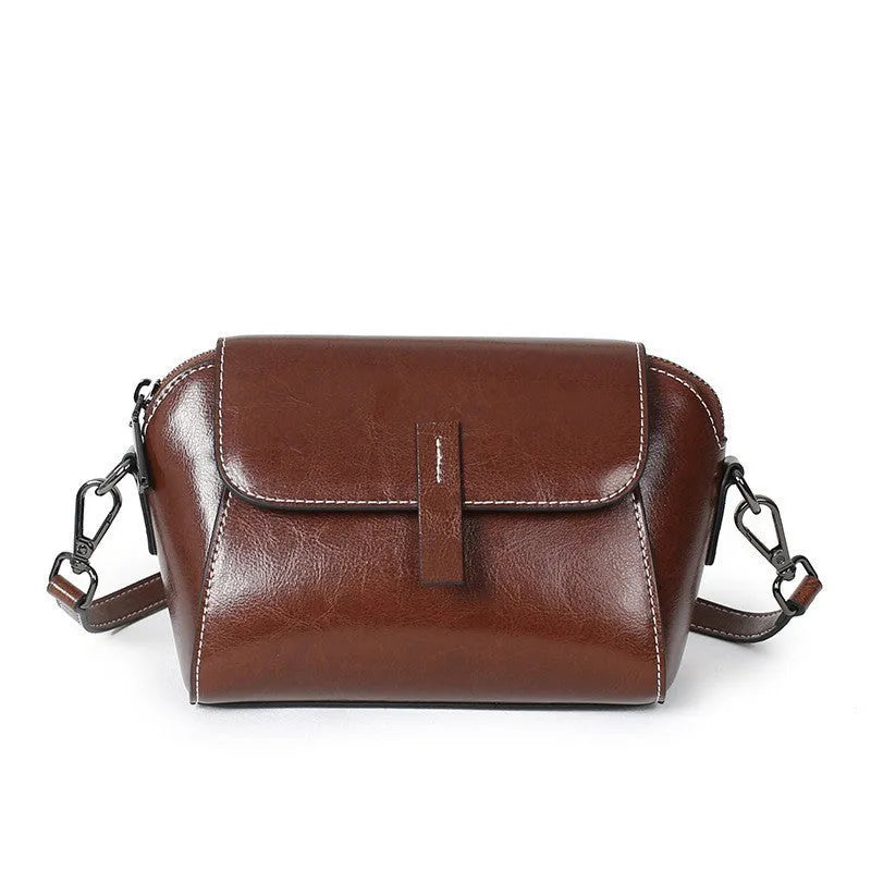 Women's brown oil wax leather shell-shaped messenger bag with a cross-body strap and front sandwich pocket.