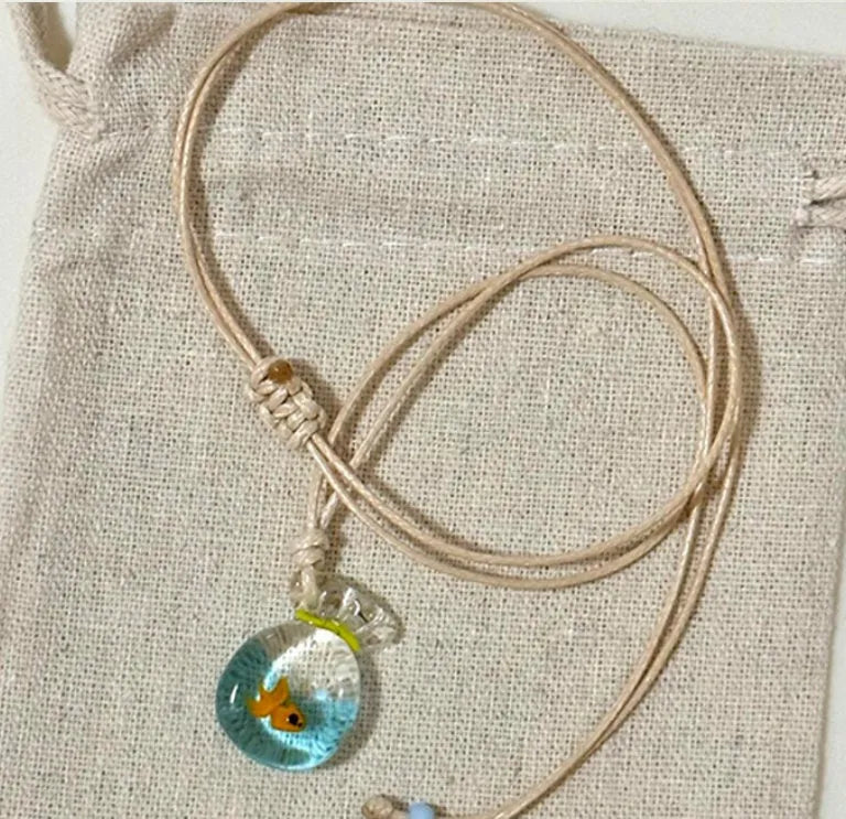 Women's necklace with coloured glaze joker pendant on a beige cotton linen clavicle chain.