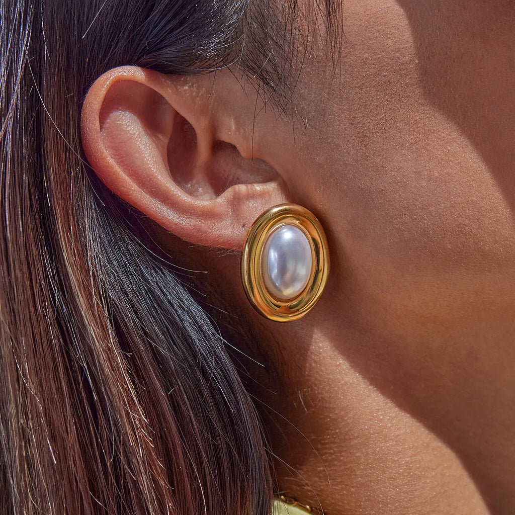 Small vintage-style pearl ear studs with a gold-tone finish on a stainless steel post.