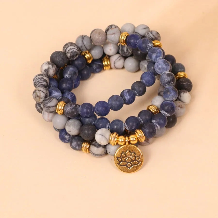 Close-up of a blue patterned network stone bead multi-layer alloy bracelet on a wrist.