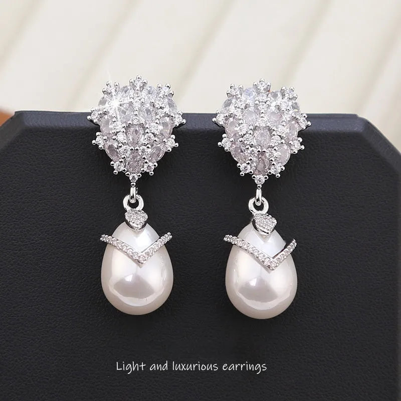 Women's drop-shaped pearl earrings with zircon stone accents and 18K gold plating.