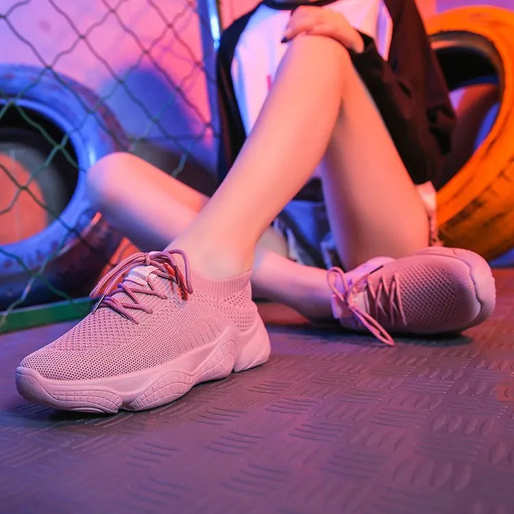 Women's white thick-soled flying woven trainers with pink perforations and a front strap on a rubber sole.