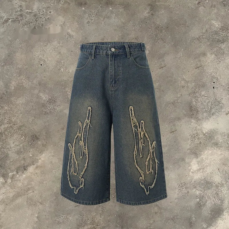 Men's black denim shorts with cropped length and flame embroidery patch design on leg