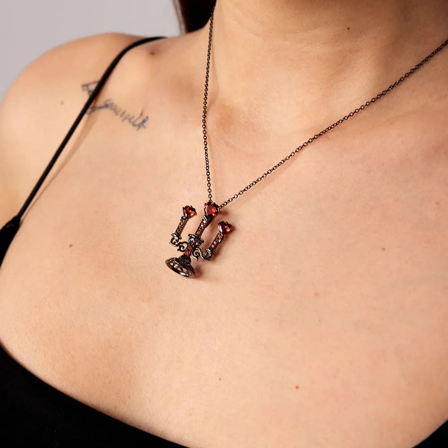 Close-up of a women's retro gothic necklace with a hollow candlestick pendant on a cross chain.