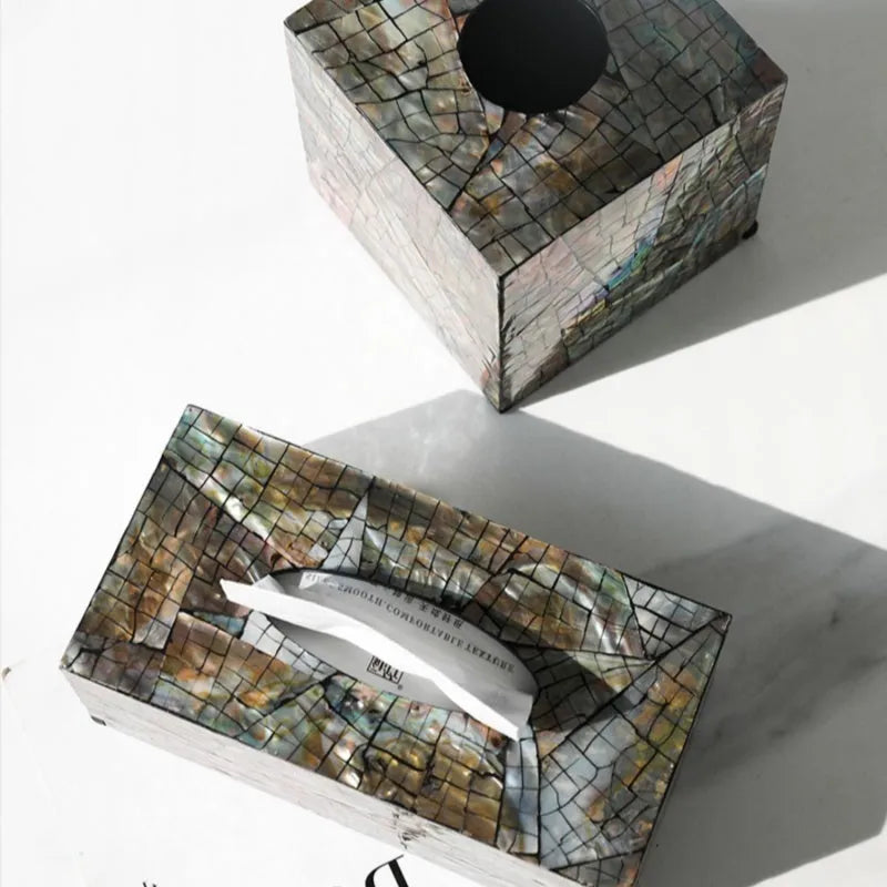 A black square shell storage box with a removable organiser insert on a coffee table.
