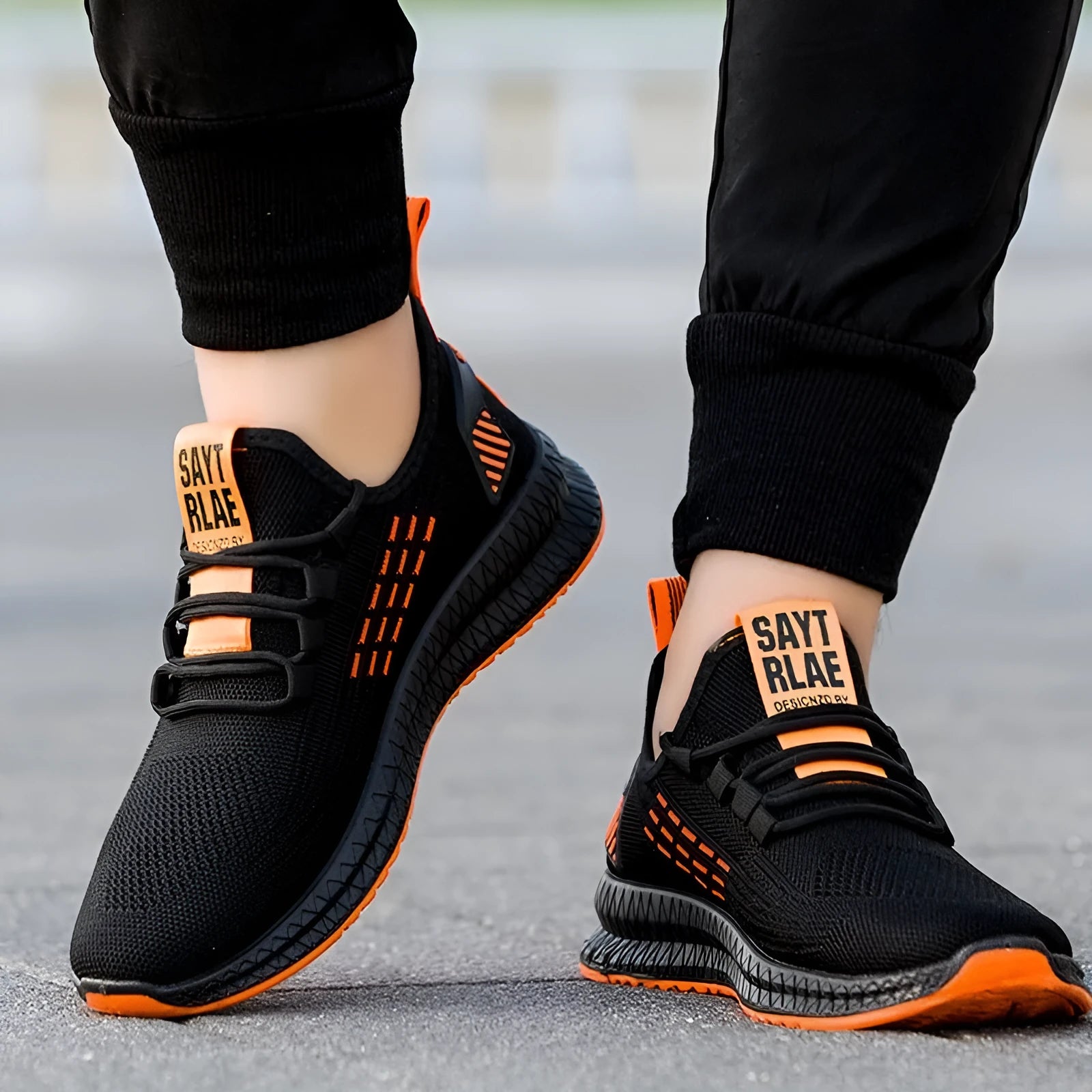 Men's fly weave casual trainers with cross-strap design and low heel in black, orange, or yellow
