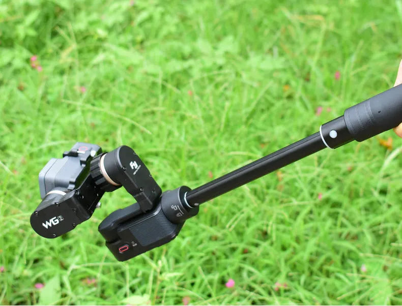Black retractable aluminium selfie stick extended with a phone attached, showing its handheld stabiliser grip.