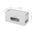 White plastic wireless router storage box with cable slots on a desk next to a router.