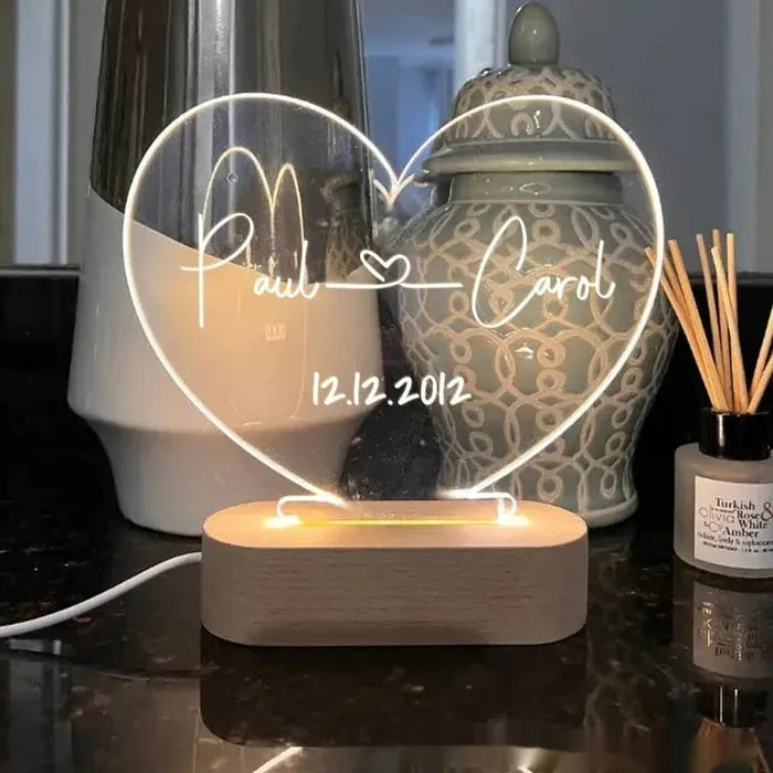 Custom transparent acrylic night light with personalised text, lit by LED, on a bedside table.