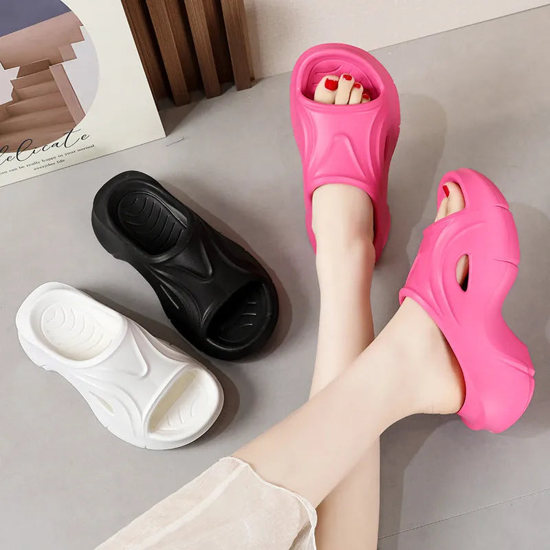 Women's white thick-soled EVA slippers on a sandy beach background.