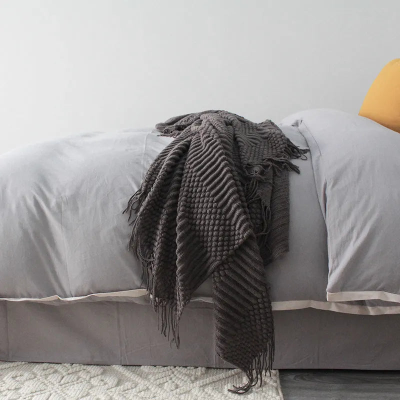 Small grey polyester nap blanket folded on a sofa, showing its size and texture.