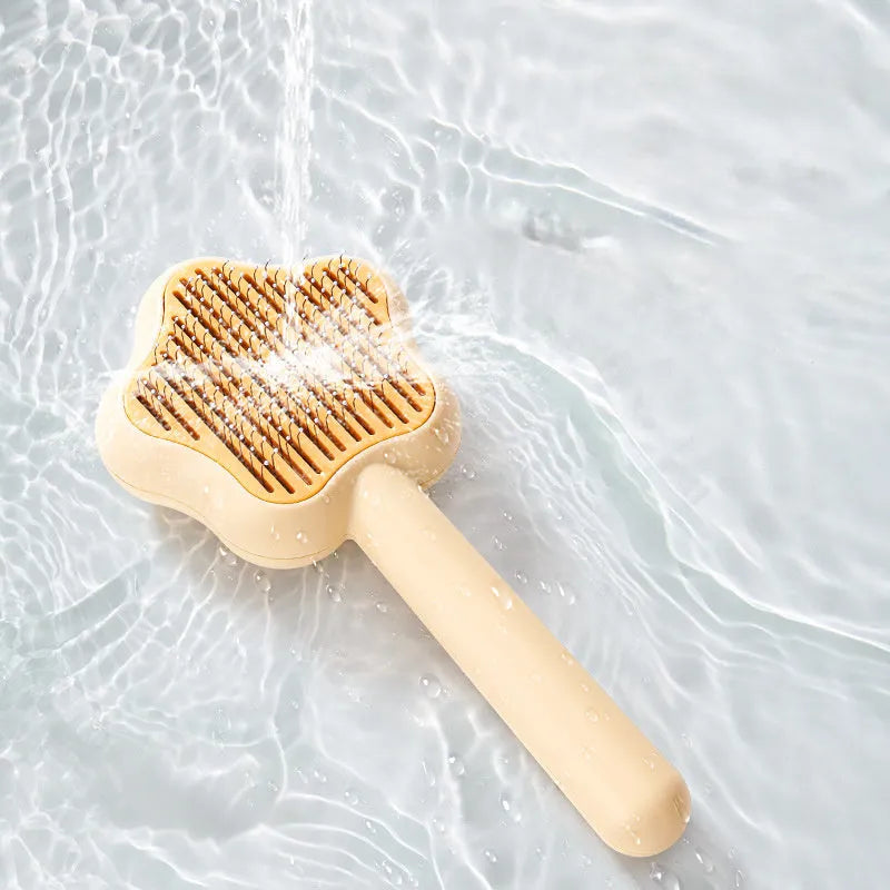 Green and yellow self-cleaning stainless steel cat comb with needle teeth on a wooden table.