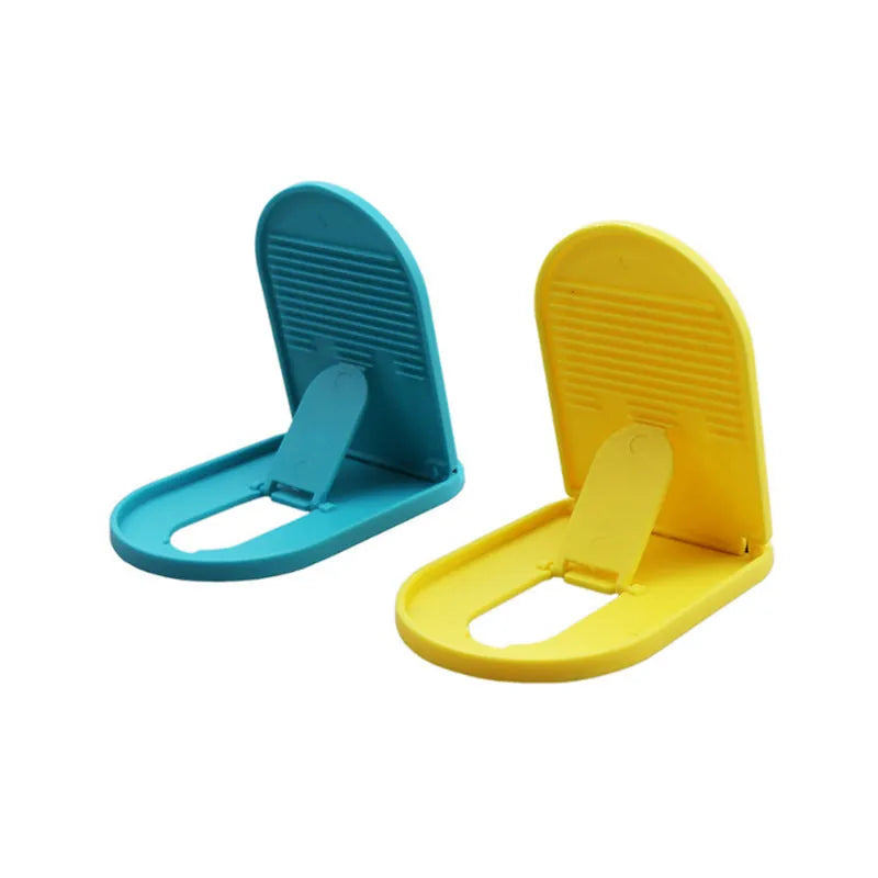 Plastic lazy bracket mobile phone stand in six colour options holding a smartphone on a wooden desk.