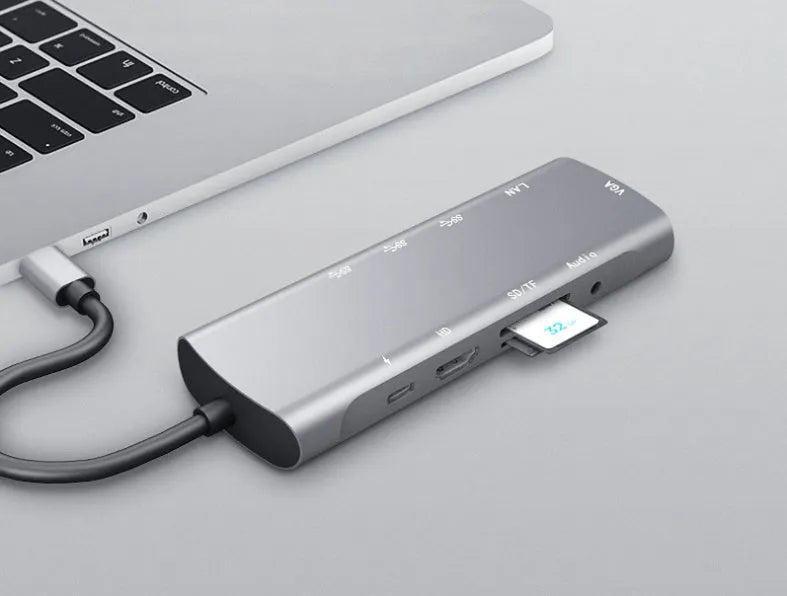 Grey aluminium USB-C docking station showing HDMI, VGA, USB, and charging ports.