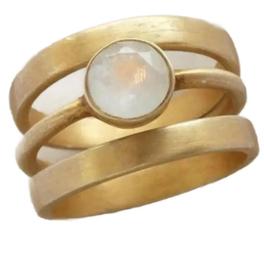 A gold geometric ring with a hollow design and a small inlaid white chalcedony stone on a titanium steel band.
