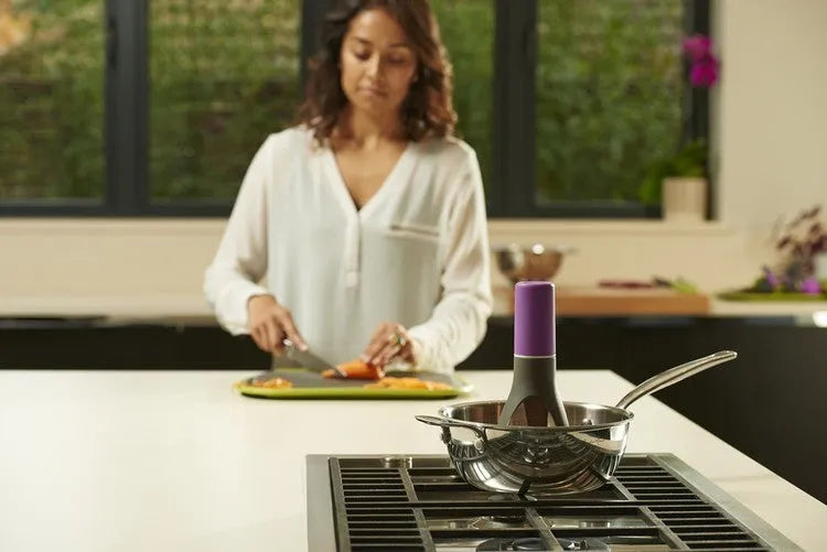 Green and grey automatic Stirr utensil for hands-free mixing in a cooking pot.