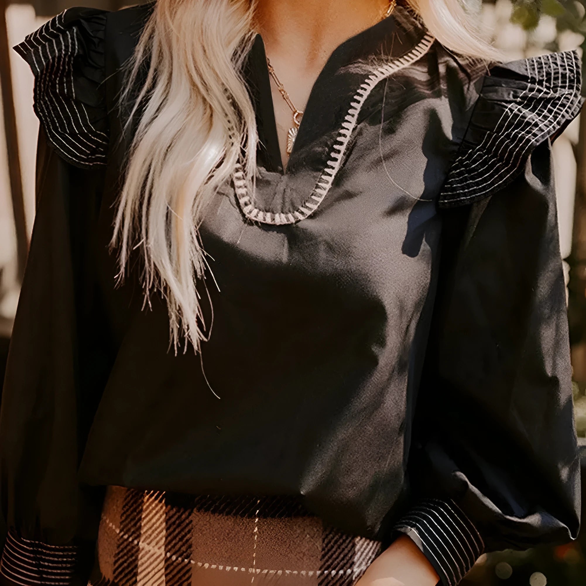 Black V-neck long sleeve blouse with contrast stitching and ruffle trim on sleeves