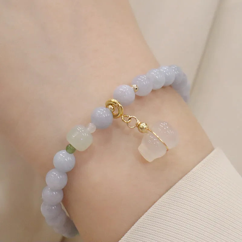 Gold plated bracelet with a detailed artificial crystal charm pendant on a woman's wrist.