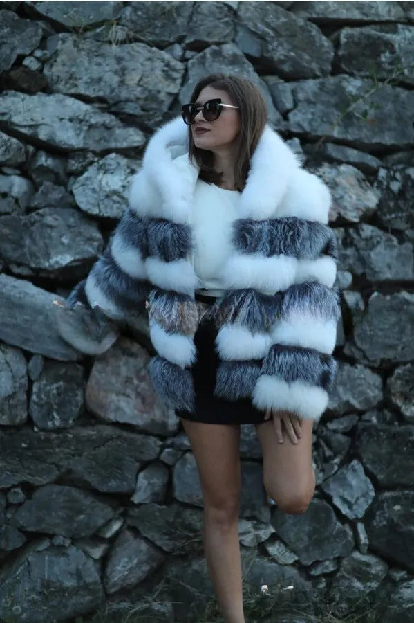 A woman wearing a loose-fit brown artificial fur hooded coat of medium length.