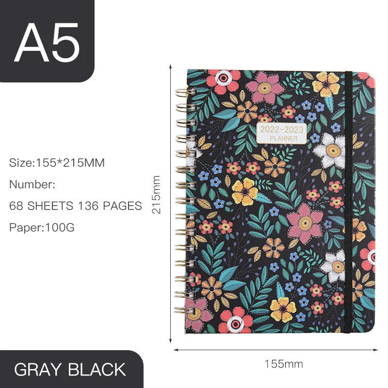 A5 spiral notebook with colourful floral cover, open to show lined pages and metal coil binding