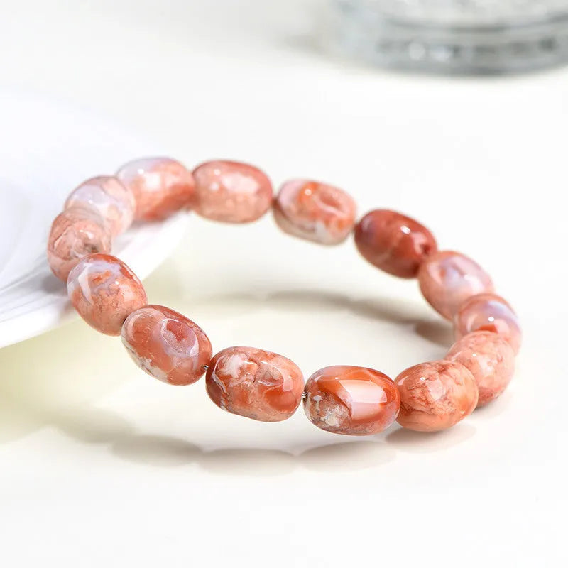 Natural cherry agate bracelet with barrel-shaped beads and a gold Ruyi charm on an adjustable strap.