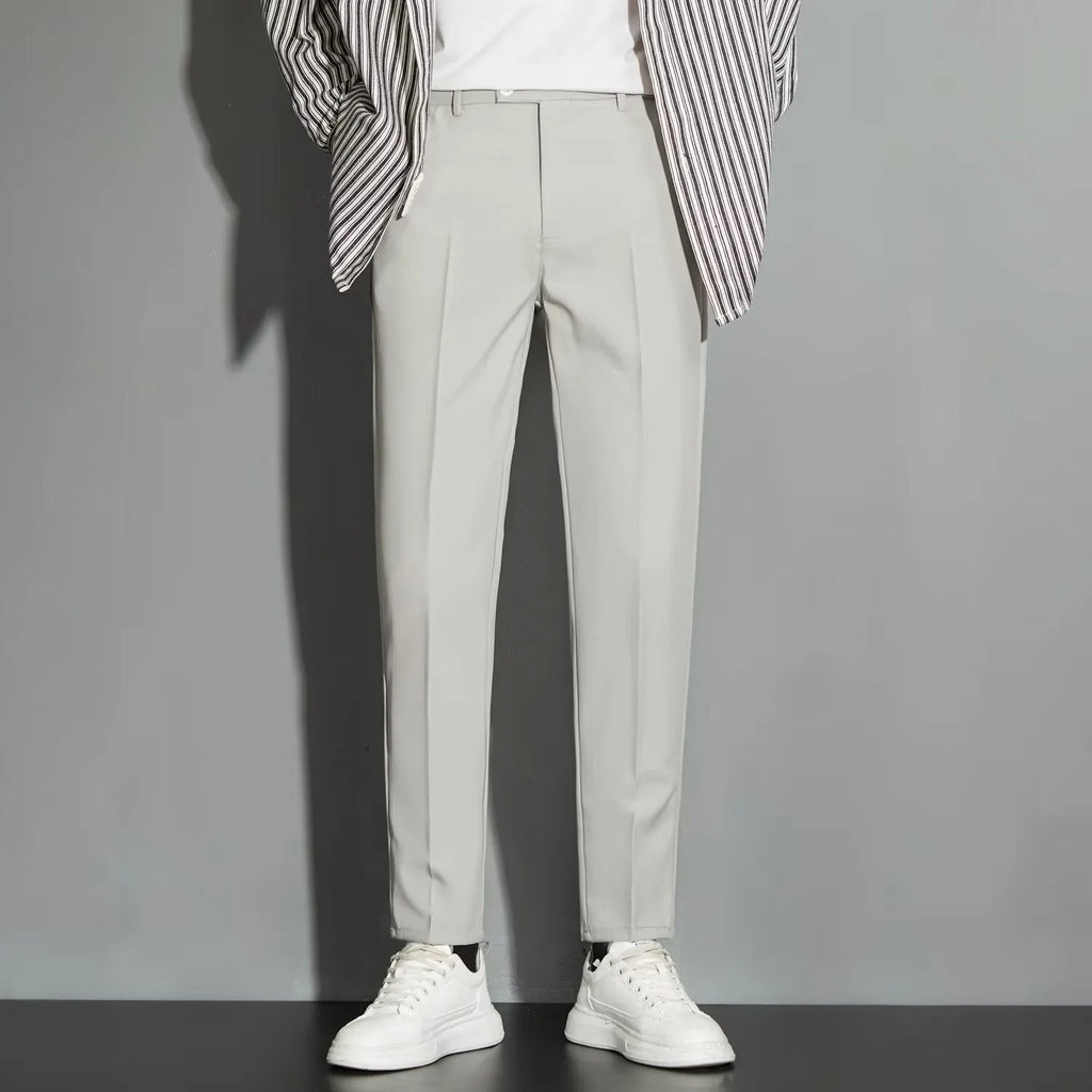 Men's straight-leg ankle-length suit trousers in a light colour showing spring draping effect detail.