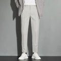 Men's straight-leg ankle-length suit trousers in a light colour showing spring draping effect detail.