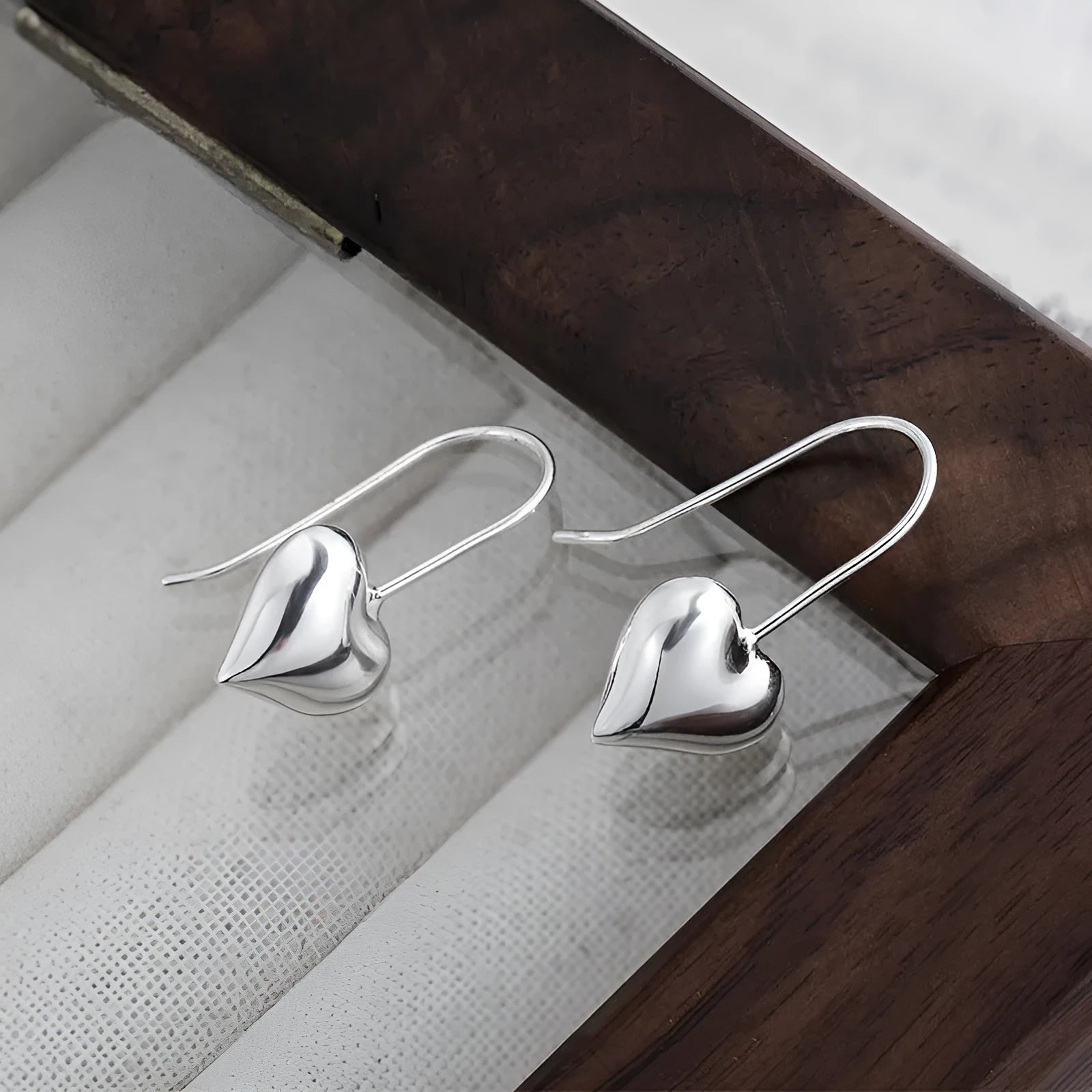 Silver coloured heart-shaped earrings with three-dimensional glossy finish and Korean style design