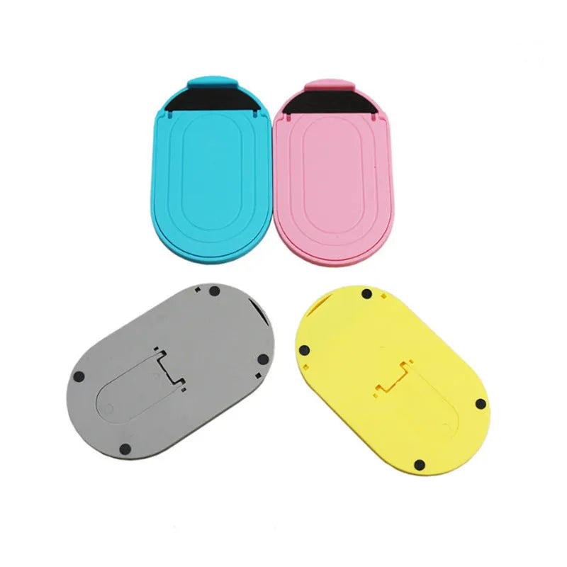 Plastic lazy bracket mobile phone stand in six colour options holding a smartphone on a wooden desk.