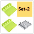 Green silicone kitchen utensil holder with four holes holding spatula, spoon, knife, and chopsticks on countertop