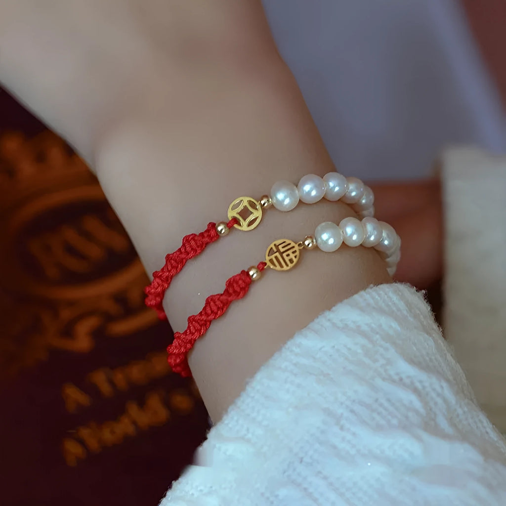Women's pearl bracelet with gold-plated fu charm on braided red rope