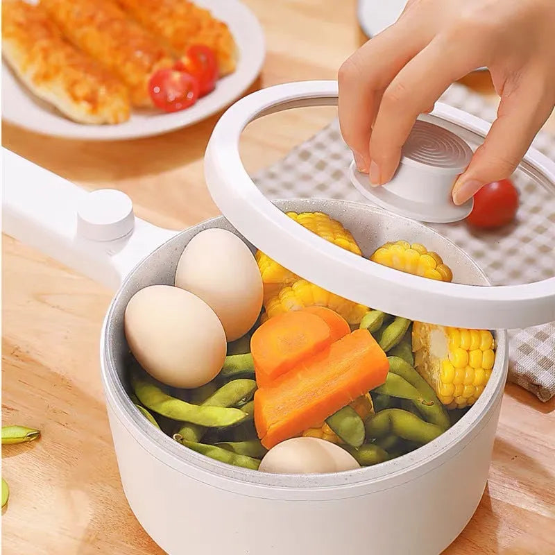 White and green multi-function electric cooking pot with temperature control dial, shown with a UK plug converter.