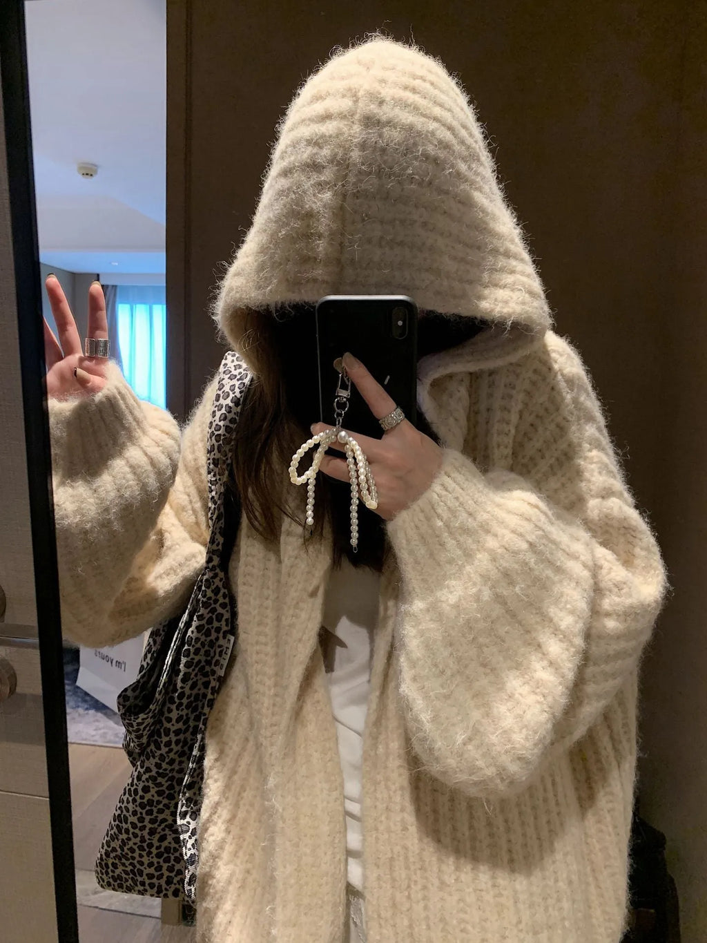 Women's loose grey hooded cardigan with a thick knit and oversized fit on a hanger.