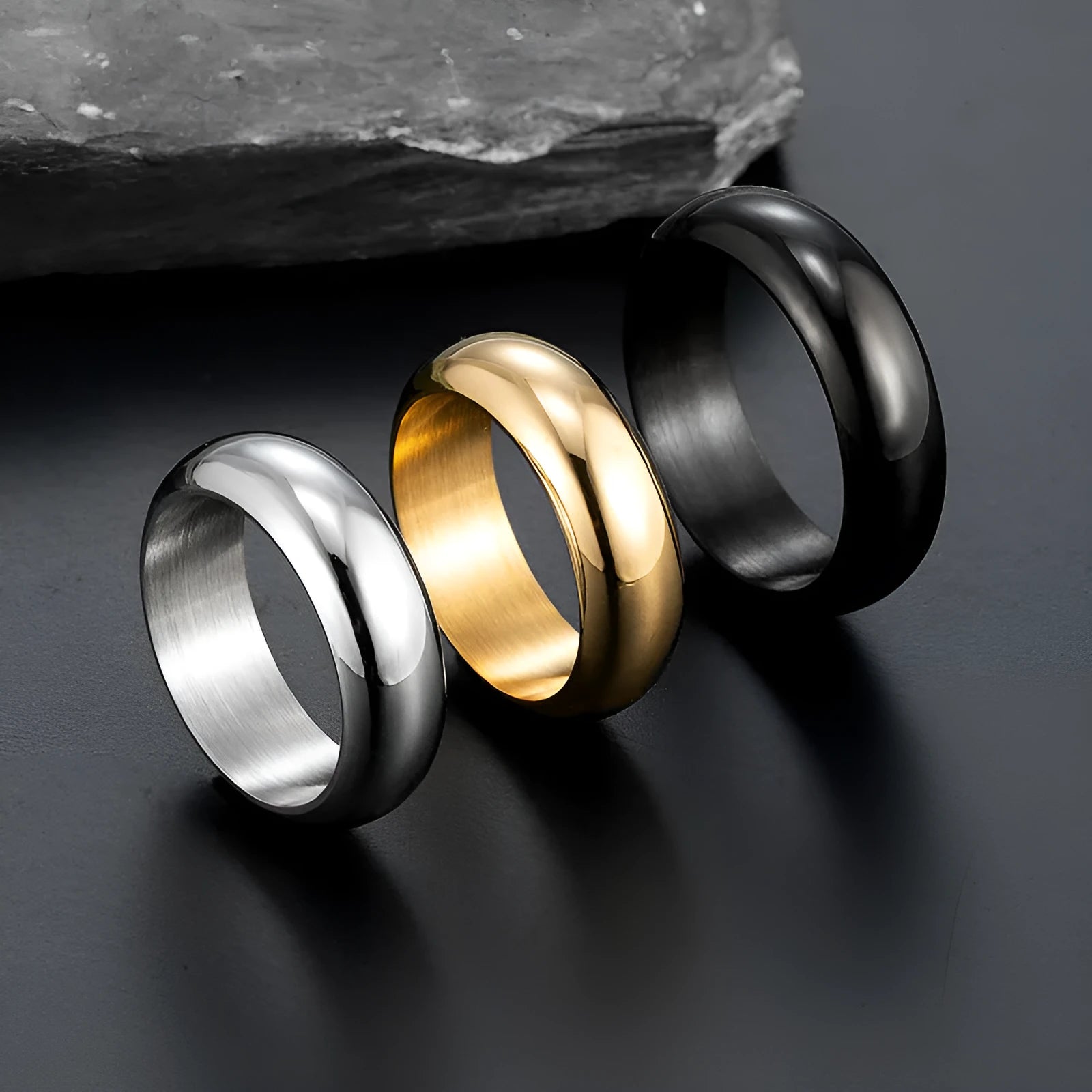 A glossy electroplated titanium steel ring shown in gold, black, and steel colour on a grey background.