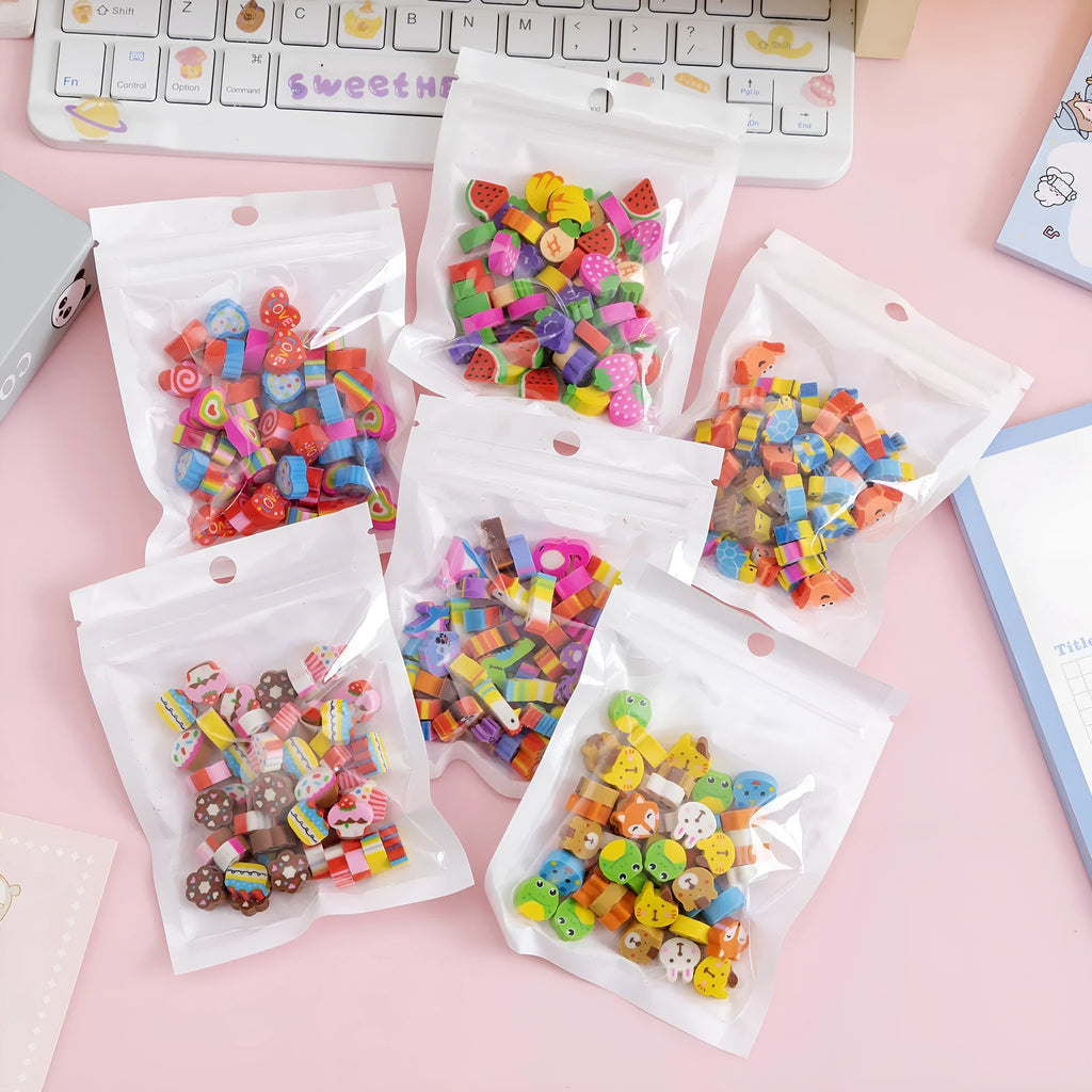Assortment of 50 colourful mini cartoon erasers in shapes of fruits, animals, and cakes on a white background.