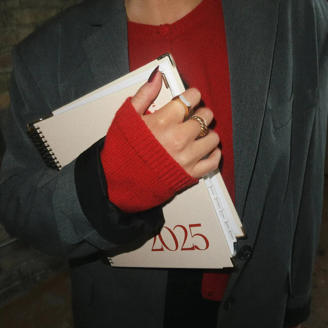 Cherry red wire-bound coil notebook with daily schedule pages open flat